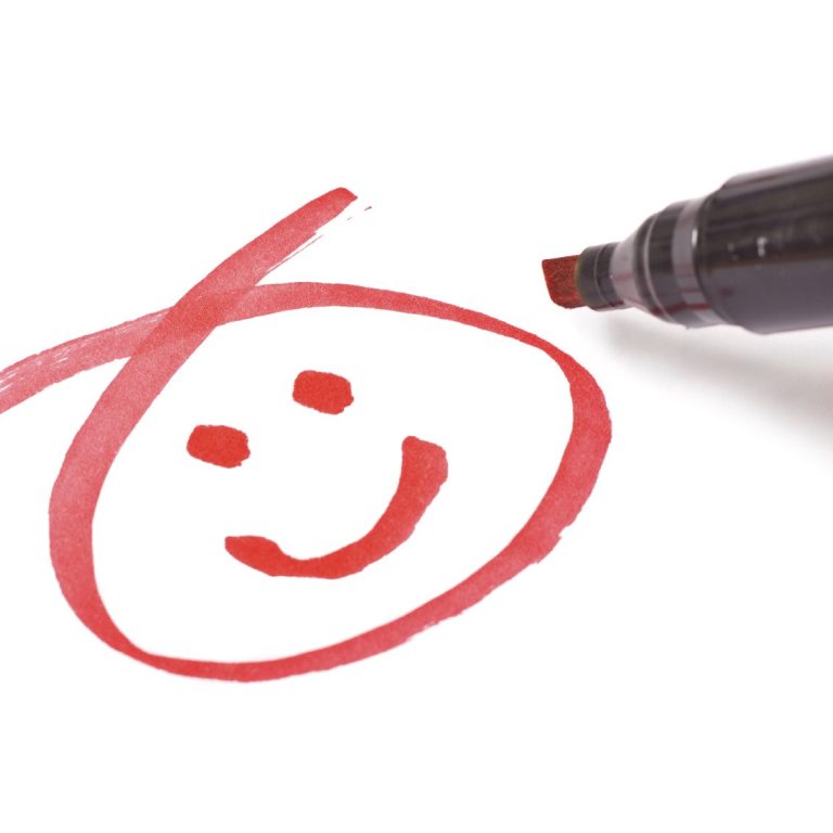 Red smiley face drawn with a marker on white paper.